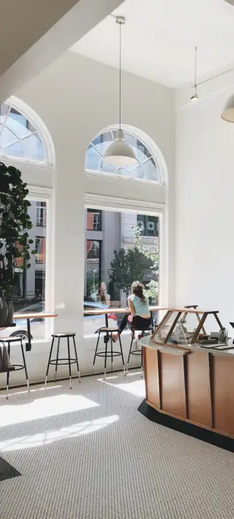 Bright café with tall arched windows, pendant lights and a wooden counter
