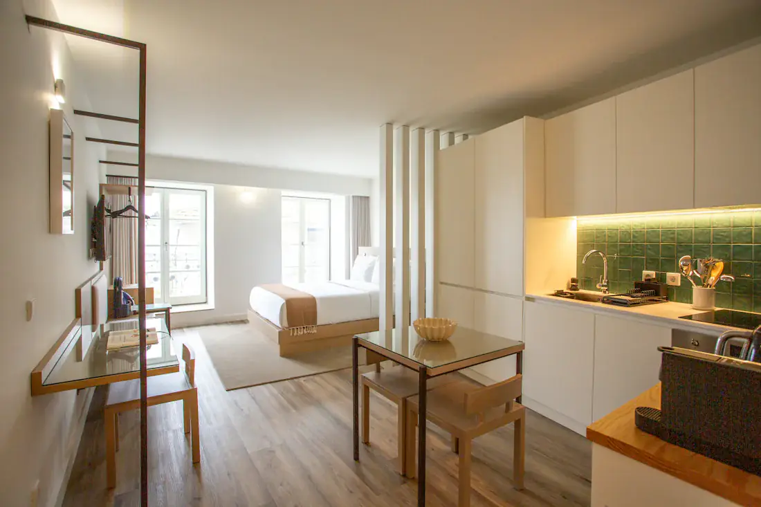 Beispielbild: größeres Studio mit Küchenzeile, Esstisch mit zwei Stühlen und Bett am Fenster
