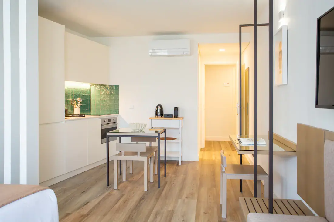 Beispielbild: Studio mit Tisch und zwei Stühlen, Küchenzeile und Vorraum, vom Bett aus gesehen